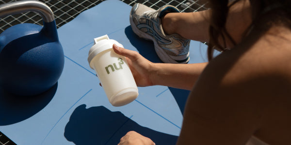 Frau mit shake in der Hand auf der Trainingsmatte